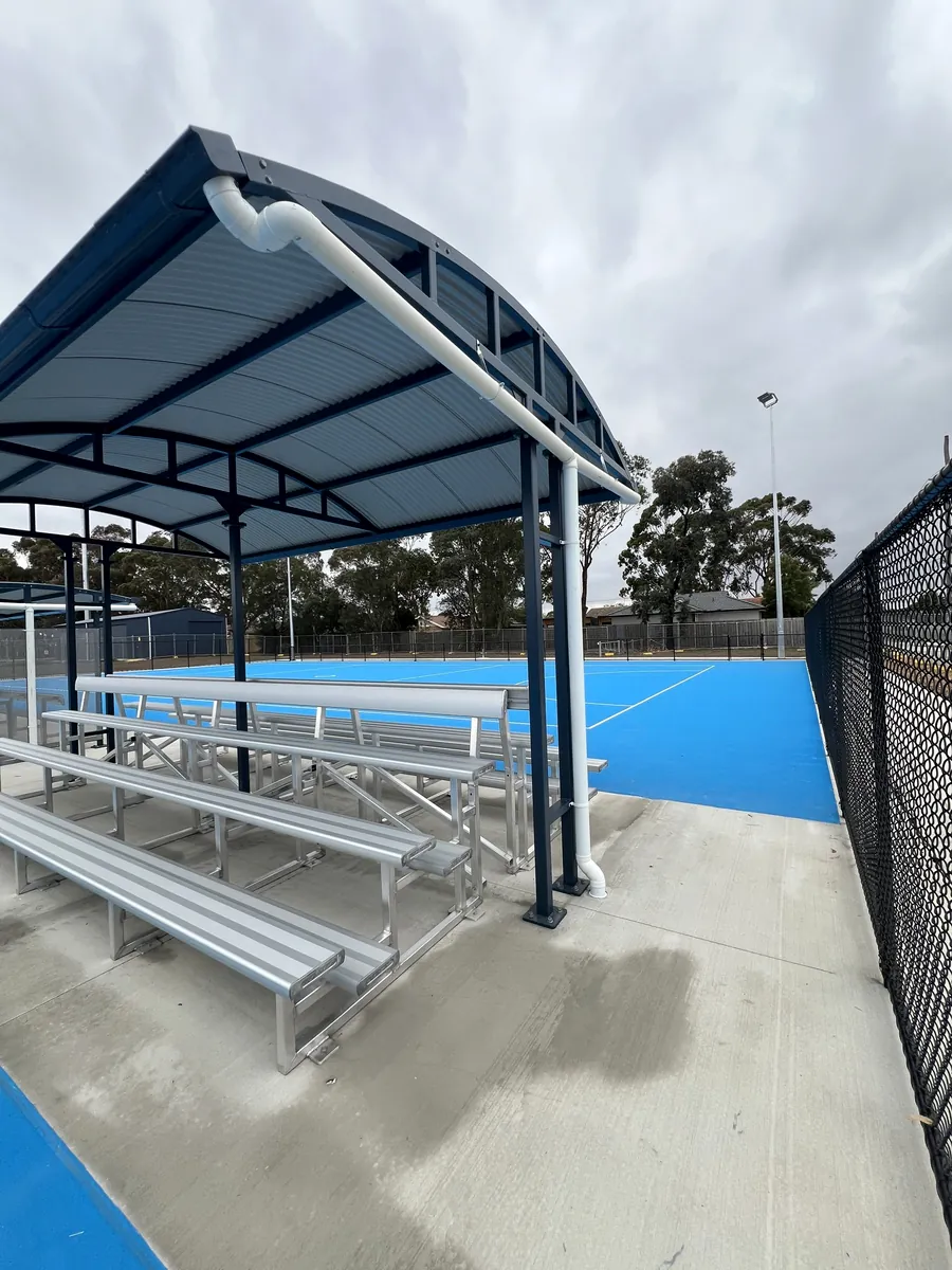 Finished netball shelter with tiered aluminium seating beside the courts